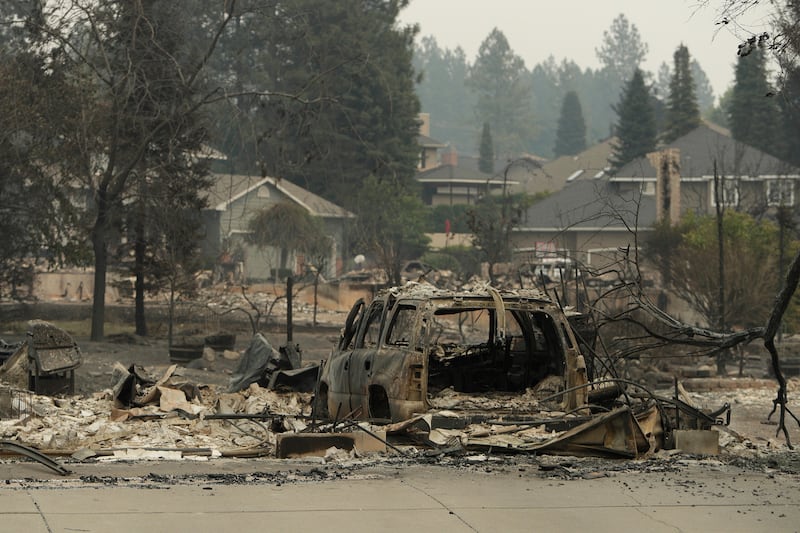 A vehicle and structure are burned on North Skyline Drive due to a wildfire, Sunday, Aug. 2, 2026, in Spokane, Washington.