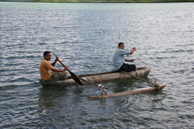On the water near Old Tonga, young men row a traditional Tongan canoe. Visitors to the village can v