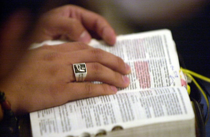 A hand rests on an open book of scripture.