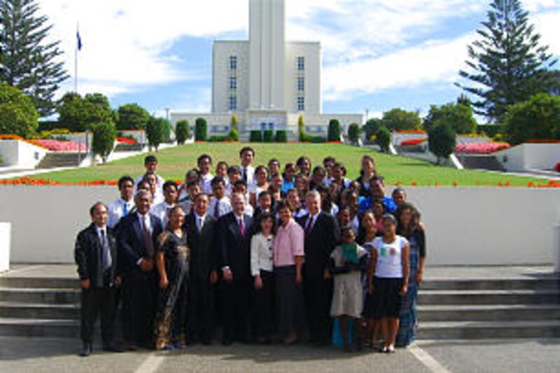 Elder and Sister Andersen stand in front of the Hamilton New Zealand Temple with a group of Church m