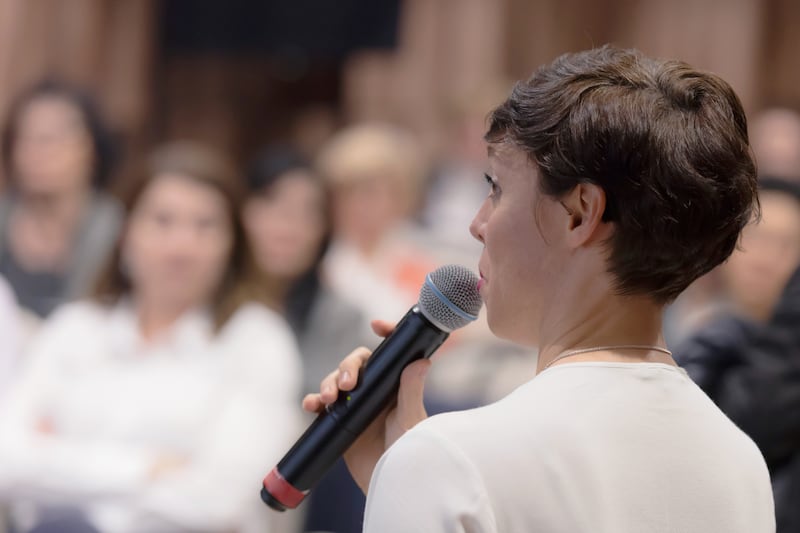 A woman uses a microphone in a class.