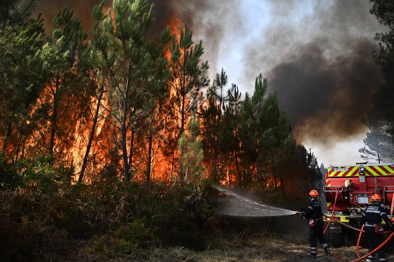 Firefighters work to extinguish a fire in the forest near Blagon, during wildfires in southwestern France, Wednesday, July 29, 2026.