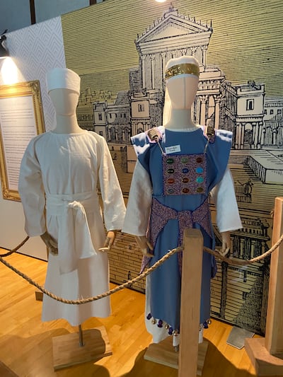 One mannequin wearing a white robe and one mannequin wearing a blue robe with 12 colored stones on the front side at the model of the ancient traveling tabernacle of Moses.