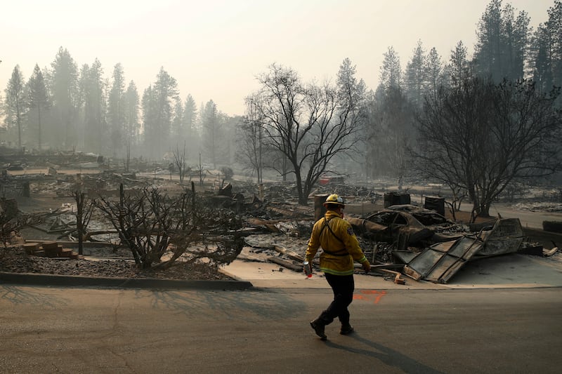 A firefighter searches for human remains in a trailer park destroyed in the Camp Fire, Friday, Nov.