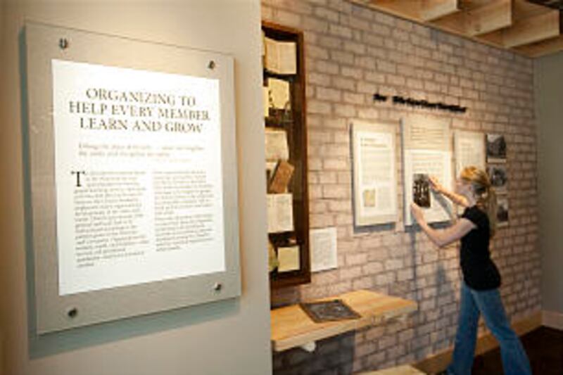 A student helps with the installation of a display included in the BYU exhibit "Education in Zion."