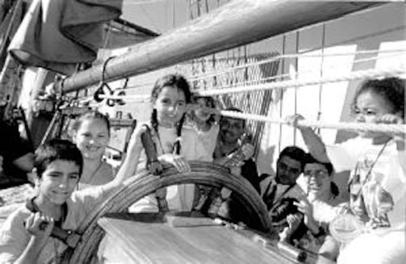 Primary children from Las Palmas District try their hands at the helm of a tall ship.