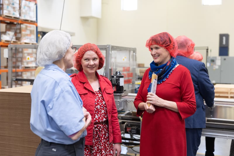 Feeding America leadership wear hairnets while touring the Church’s Deseret Mill and Past Plant. One woman holds a package of pasta.