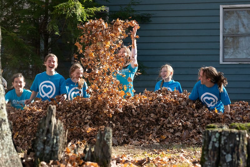 Sister Andrea Muñoz Spannaus plays in autumn leaves with five teenagers during a JustServe project in Tennessee.