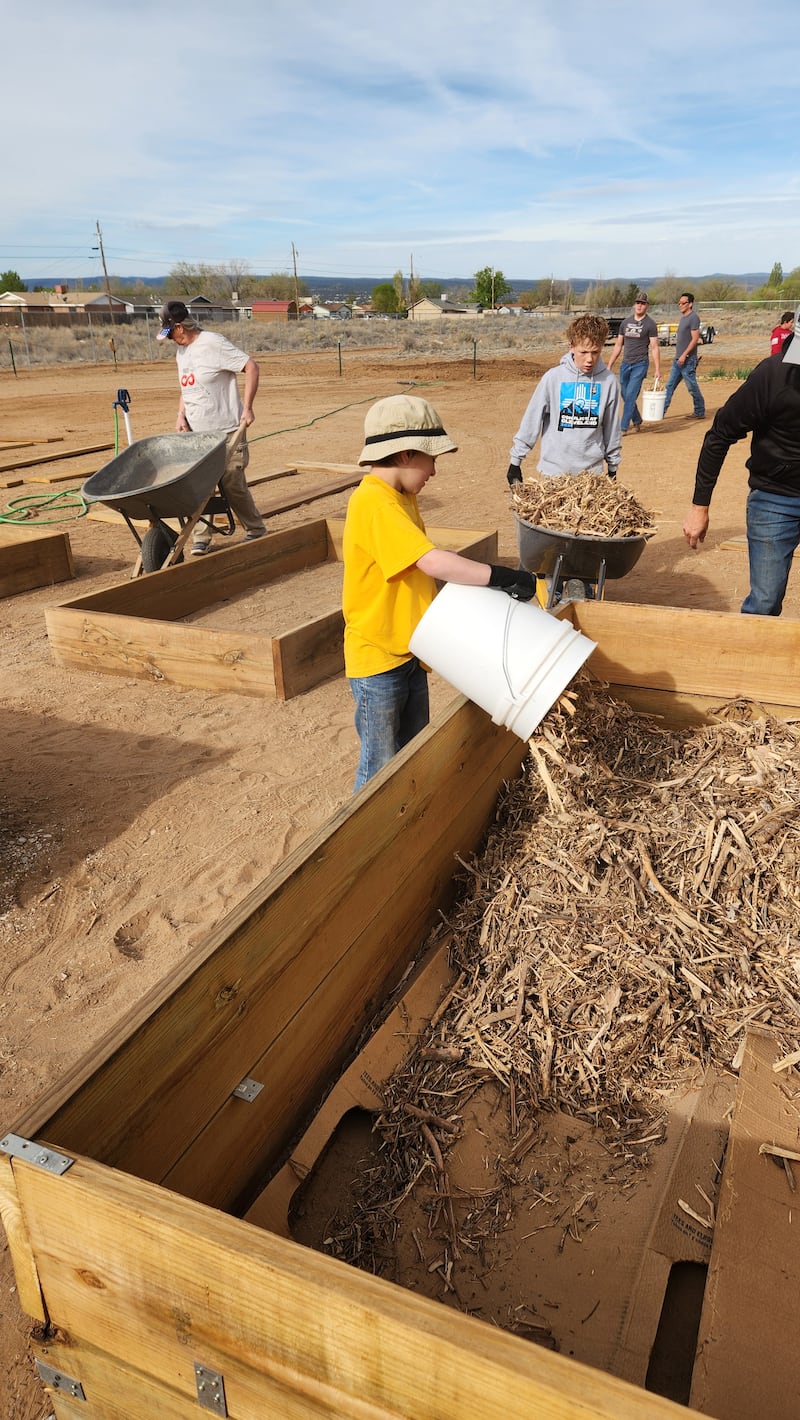 Youth and adults prepare new garden boxes at the Community Pantry and Hope Garden in Grants, New Mexico, on April 11, 2026.