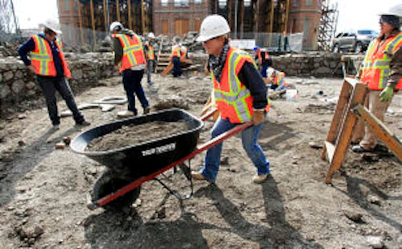BYU student Shelley Watts pushes a wheelbarrow of sifted dirt away from the dig area.