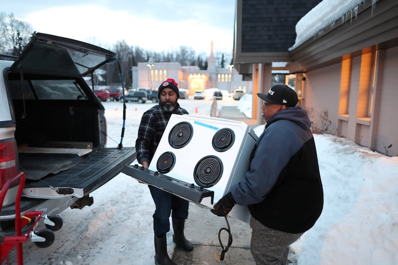 Members from the New Hope Baptist Church carry a stove out to their truck in Anchorage, Alaska.