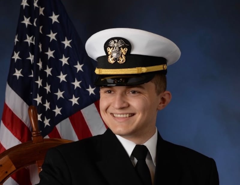 Ensign Jared Davenport in uniform in front of an American flag.