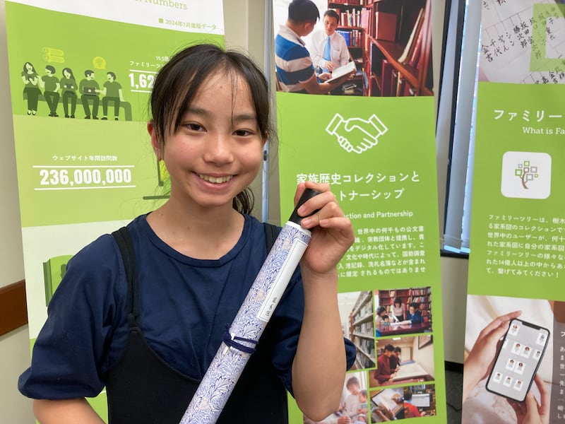 A young girl shows off a genealogy scroll she made during a family history fair in Kagoshima, Japan, Feb. 23, 2026.