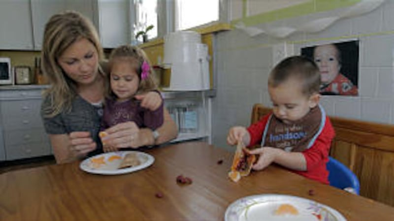 Lynzie Allen helps her daughter, Evelyn, eat lunch.