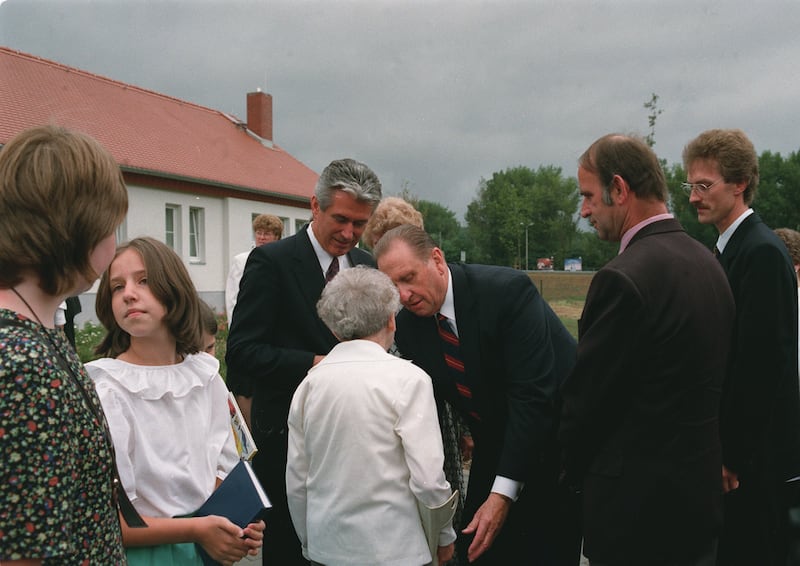 Elder Uchtdorf stands left of President Thomas S. Monson as he greets a widow in Goerlitz, Germany, 1995.
