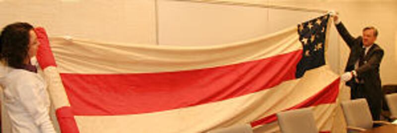 GEO. A. SMITH FLAG, first to fly over parowan. held by Richard Oman and Sarah Sorenson.