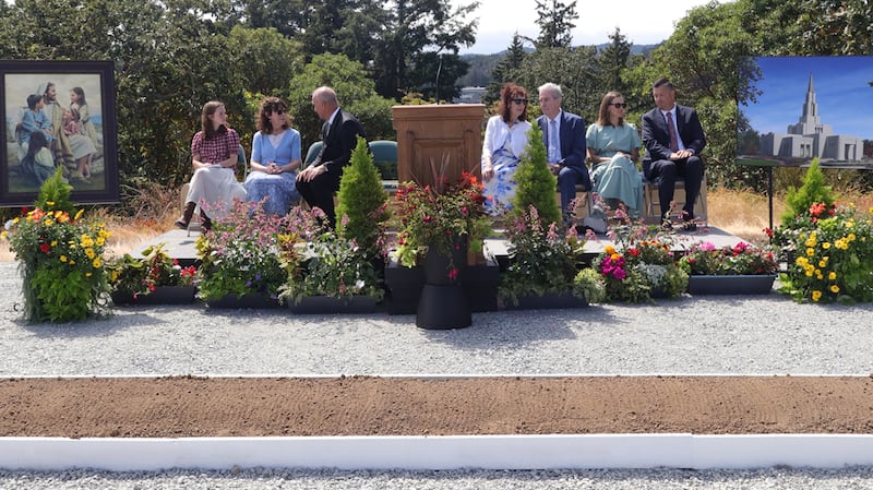Elder James E. Evanson, a General Authority Seventy and member of the Church’s Canada Area presidency, third from left, talks with the youth speaker Vienna Wigg and pioneer speaker Marilyn Hall Terry before the groundbreaking ceremony of the Victoria British Columbia Temple on Saturday, Aug. 22, 2026, in Langford, British Columbia. Others on the stand are Graham and Lyanne Sanderson, co-chairs of the groundbreaking committee, and Elder M. Shayne Olsen, Area Seventy, and his wife, Sister Cyndy Olsen.
