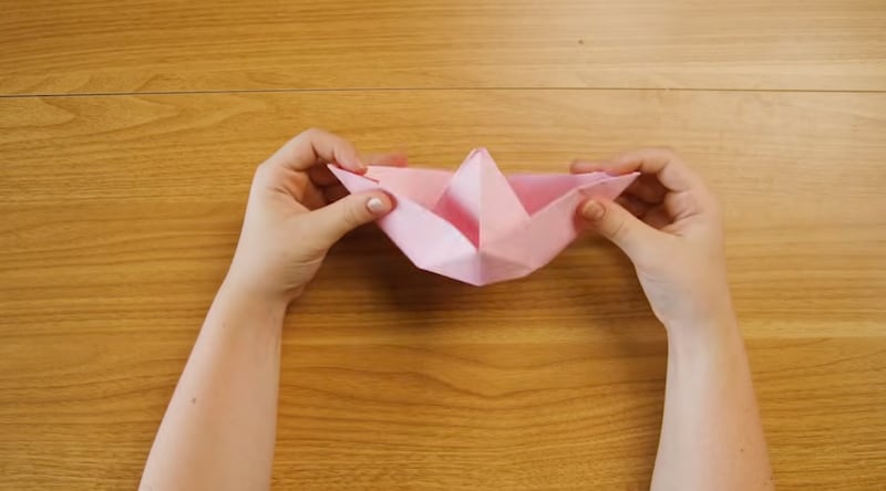 A child folds a paper into the shape of a boat like Noah's ark.