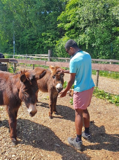 Elder Daniel Miller pets a donkey at the Huddersfield Horse & Donkey Rescue Sanctuary in Huddersfield, England, in 2025.