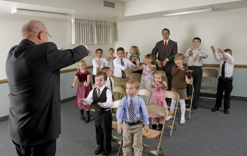 Primary children follow the chorister during singing time.
