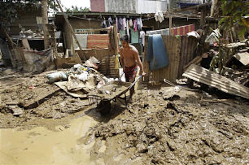 A Filipino man removes mud out of his home in Rizal province, east of Manila, Philippines on Sunday,