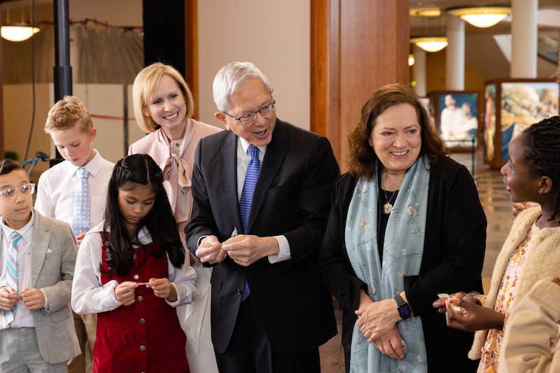 Elder Gerrit W. Gong, Sister Susan Gong and Sister Amy A. Wright open fortune cookies with children during the filming of the May 2026 Friend to Friend.