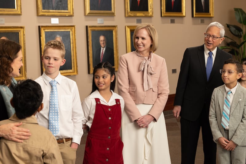 Elder Gerrit W. Gong, Sister Susan Gong and Sister Amy A. Wright talk with four children in the Conference Center in Salt Lake City during the filming of the May 2026 Friend to Friend.