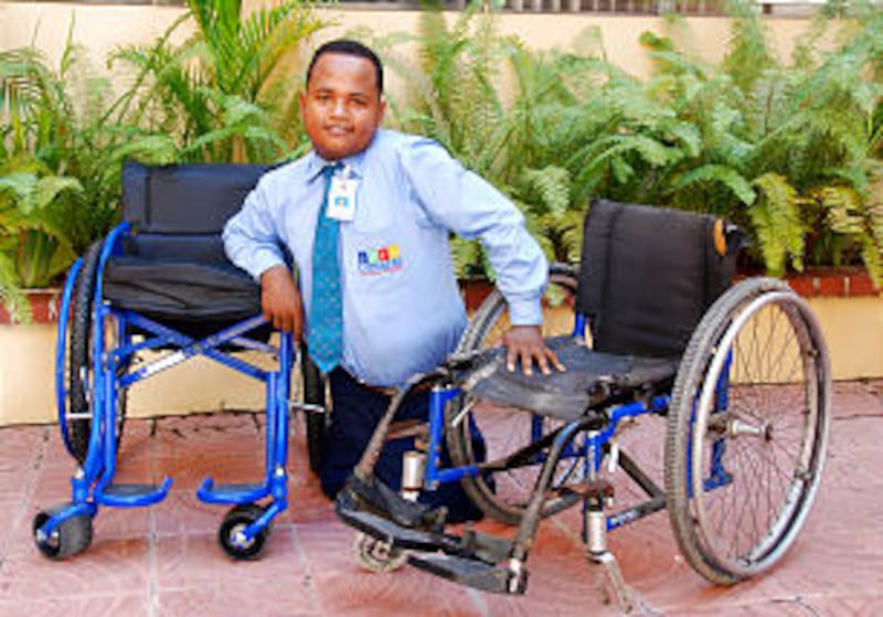 Jose "Riqui" Perez poses with his old worn-out wheelchair and his new Roughrider wheelchair provided