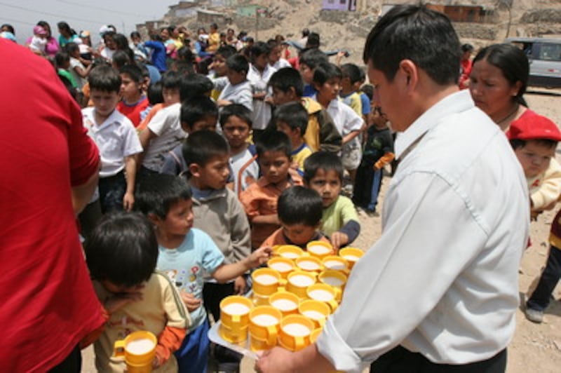 A worker with the Johannes Gutenberg Cultural Association passes out mugs of oatmeal to impoverished