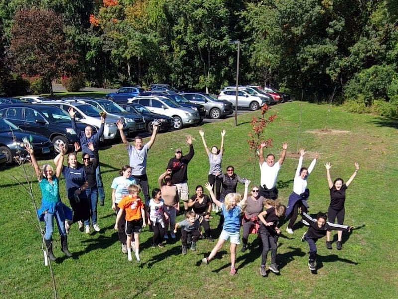 About two dozen members of the Fairfield Connecticut Stake jump on a grassy field for a drone shot of their tree-planting efforts.