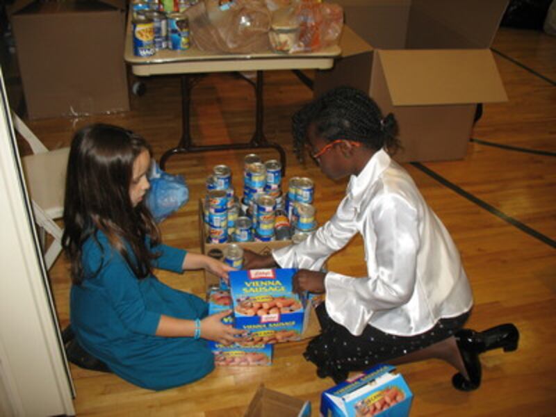 Six year-old Brianna Capote and 10 year-old Joyce Laurent sort out cans to be boxed.
