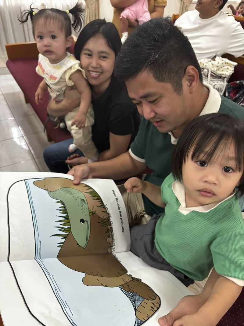 A family reads a book about nutrition during the first Child Nutrition Program screening held at the Caloocan Philippines Stake Center on Jan. 24, 2026.