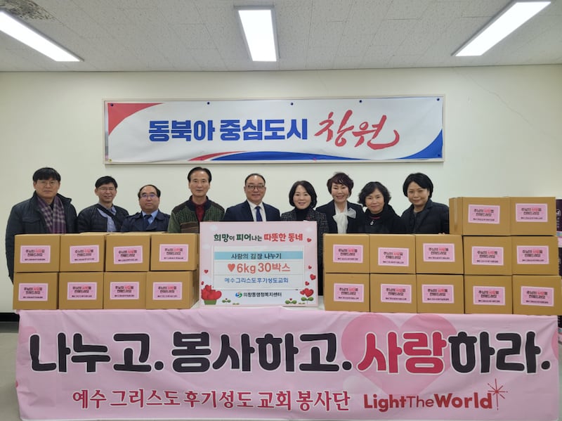Leaders from the Changwon area, Masan University and various charities stand behind boxes of prepared kimchi in Changwon, South Korea, on Dec. 12, 2025.