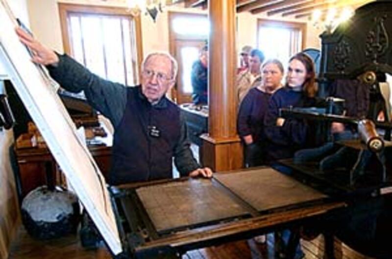 Elder Harold Dance explains to visitors at the printing office how the newspaper was produced.