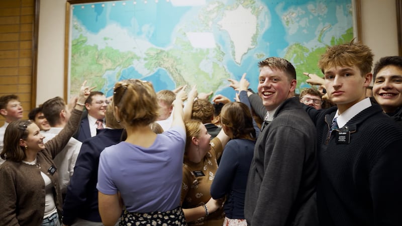 Missionaries point to their assigned mission on a world map during the filming of a new video at the Provo Missionary Training Center.