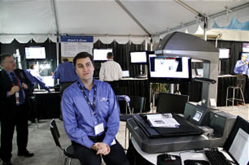 At a show booth, M. Scott Simpkins of FamilySearch describes scanning technology being used to prese
