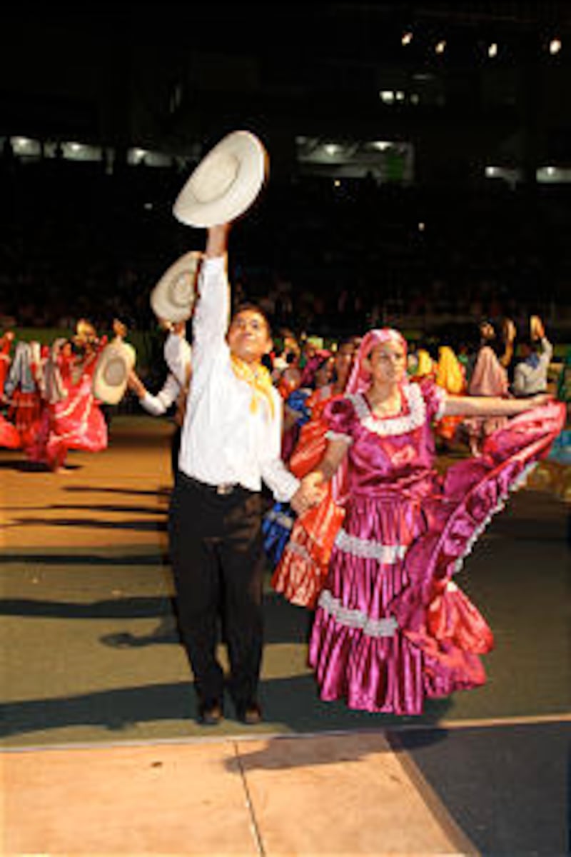 Young performers in traditional Salvadoran dress salute audience members following a spirited dance.