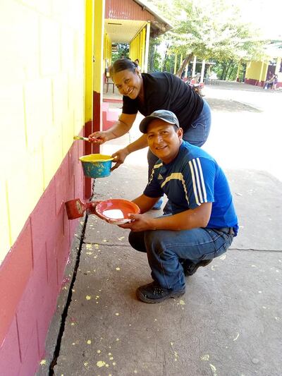 Community members help paint at their local school in Guatemala as part of a project to upgrade the schools sponsored by the SOYLA Foundation.