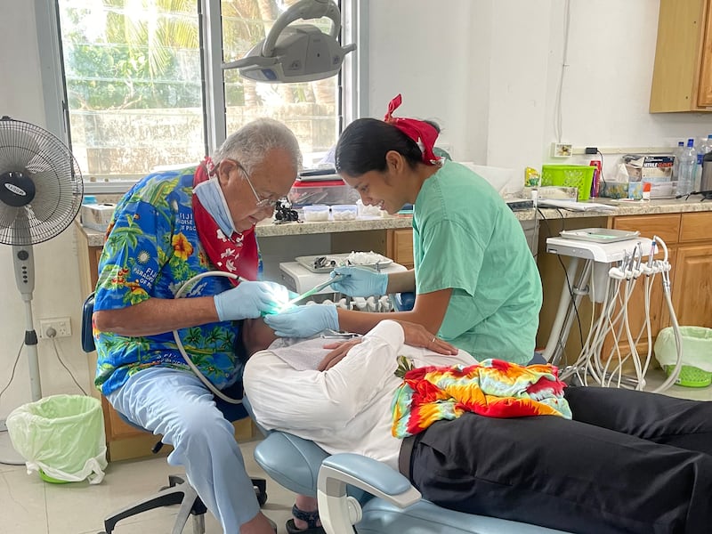 Wayne Chisholm works on a patient's teeth at the Moroni clinic in Eita, Kiribati, 2024.