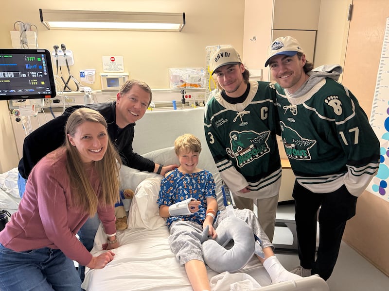 Nate Cooper, age 9, center, the son of Allie and Lee Cooper, left, get a visit from idaho Steelheads hockey players Nick Canade and Ty Pelton-Byce of the Idaho Steelheads hockey team at the St. Luke's Children's Hospital in Boise, Idaho, on March 10, 2026.