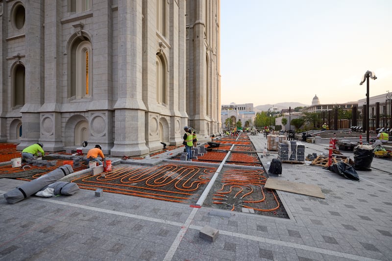 Crews install stone pavement on top of snowmelt tubing outside the Salt Lake Temple in Salt Lake City on Tuesday, June 23, 2026.