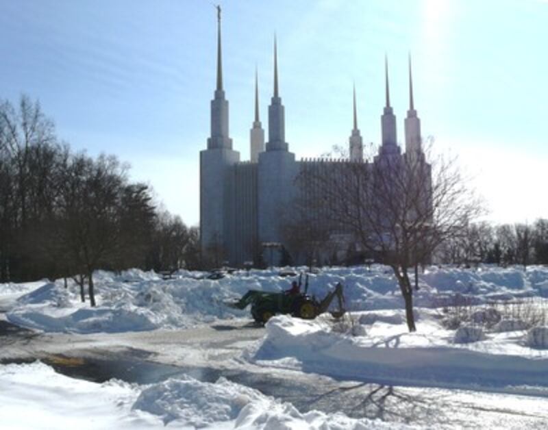 A tractor continues in the effort to move snow from the temple grounds. The parking lot is partiall