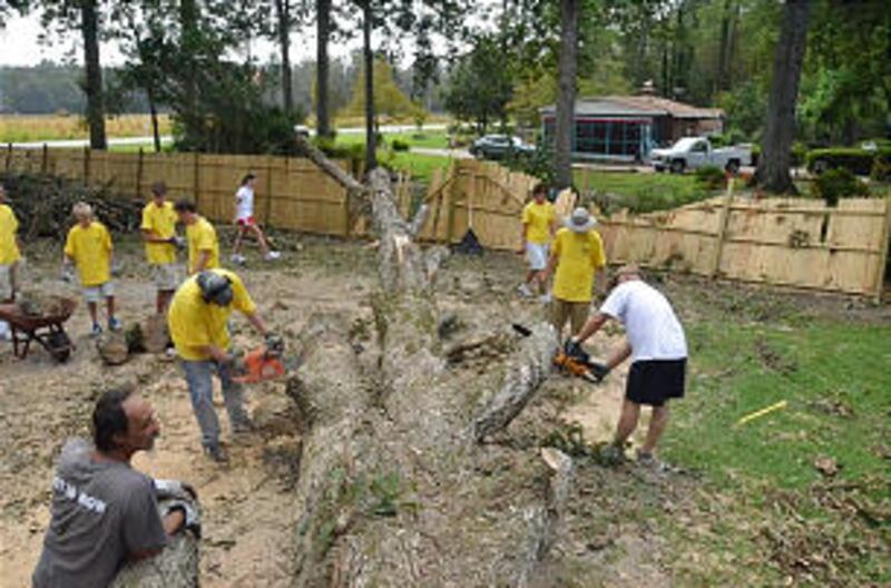Church volunteers participating in a Sept. 3 service project clear away a large fallen tree in the y