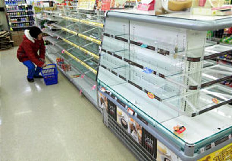 A woman looks at what food is available on the shelves in a local store in the tsunami damaged town