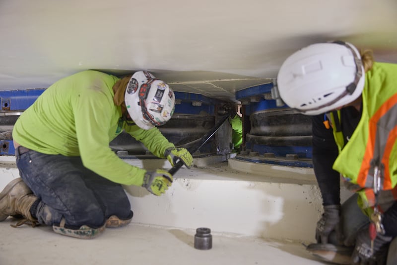 Crews remove bolts from one of the plates of a base isolator located 20 feet below the Salt Lake Temple in Salt Lake City on Thursday, June 25, 2026.