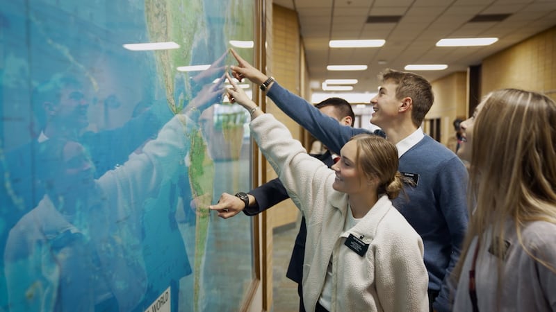 Missionaries point to their assigned mission on a world map during the filming of a new video at the Provo Missionary Training Center.