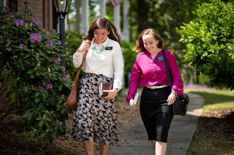 Two sister missionaries of The Church of Jesus Christ of Latter-day Saints walk down a street in Georgia.