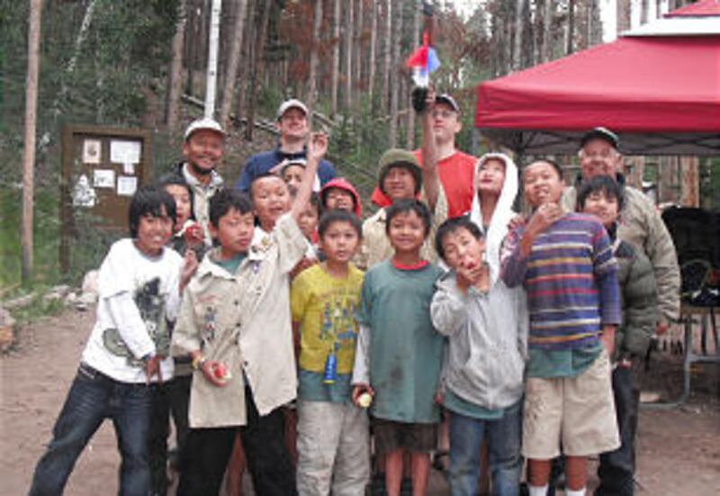 Burmese Scouts from Troop 1262 raise the Tomahawk Award they were bestowed at Utah's Camp Tomahawk.
