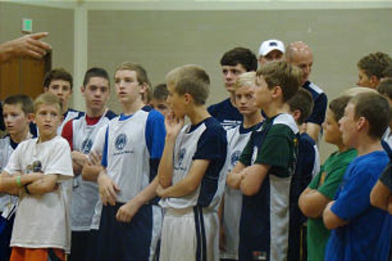 Young men and their dads listen attentively to basketball instruction at the 2013 BYU Fathers and So