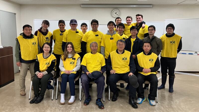 Around 20 Church members and missionaries wear yellow Helping Hands for a picture after cleaning up at an evacuation center in Japan.